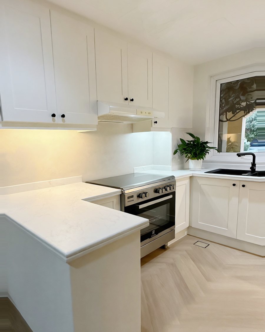 Kitchen after RINOVA refinishing: white cabinets and marble-effect worktop
