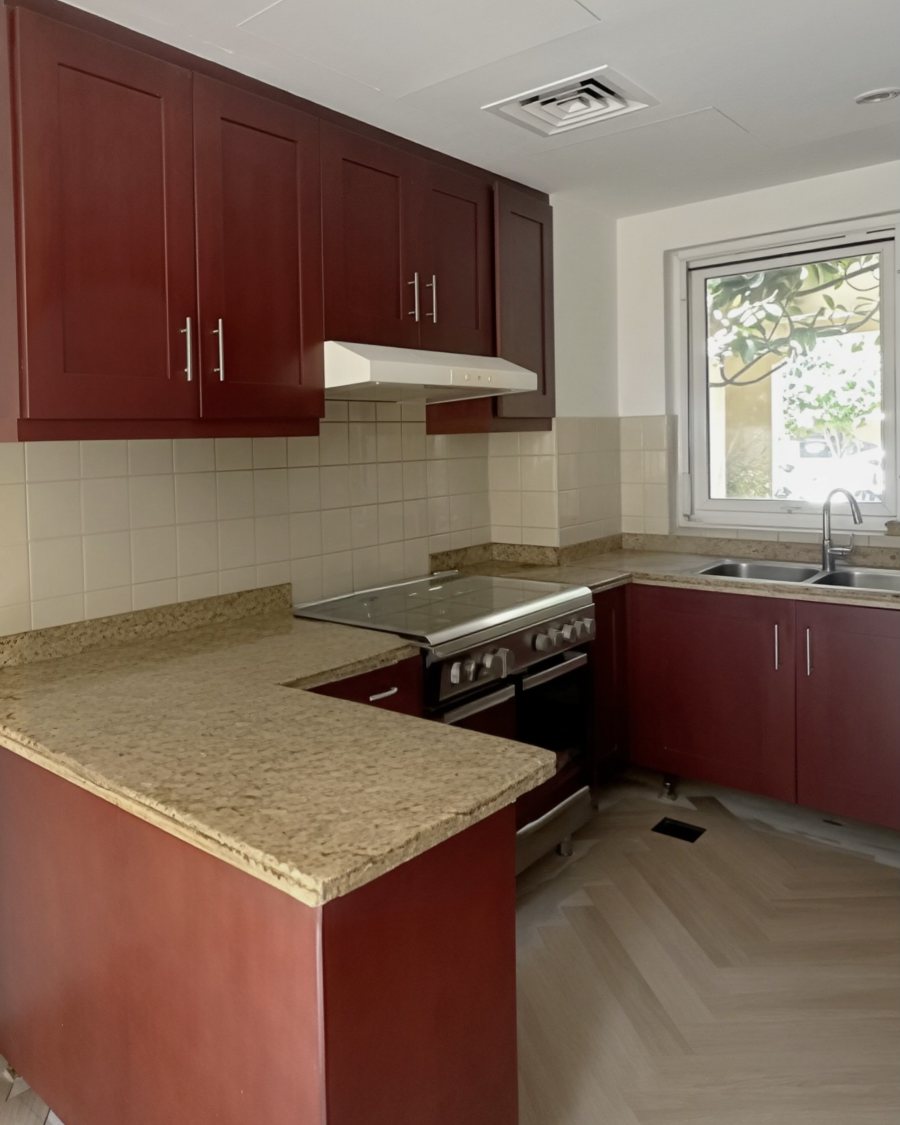 The same kitchen before refinishing: dark red cabinets and granite worktop